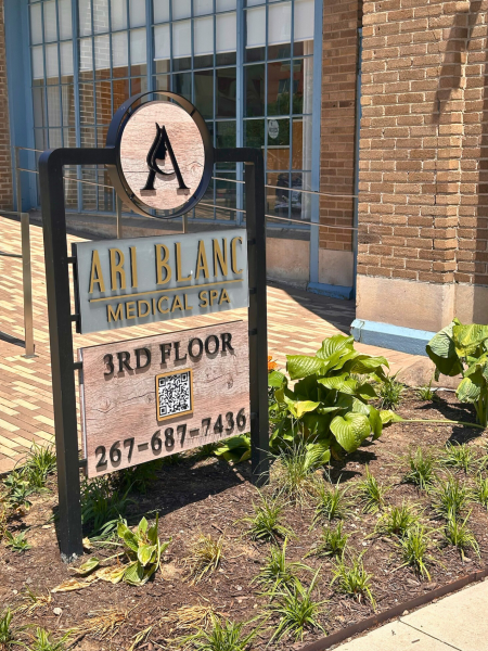Freestanding Ari Blanc Medical Spa sign with logo, “3rd Floor,” QR code, and phone number in front of Pier 5 brick facade.