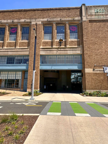 Exterior of the 1923 brick Pier 5 Municipal Pier building on Columbus Boulevard, showing large industrial windows, a star-shaped “Pier 5” sign, and the main double-door entrance beyond a green-striped pedestrian crosswalk.