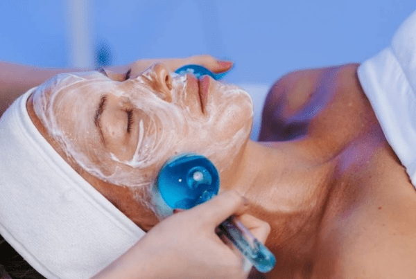 Client receiving a Calm and Restore Facial with cooling globes and a hydrating cream mask to calm sensitive skin, support barrier repair, reduce redness, and restore hydration.